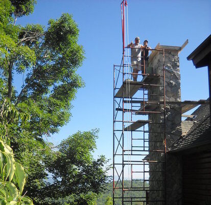 Scaffolding and two men restoring a stone chimney