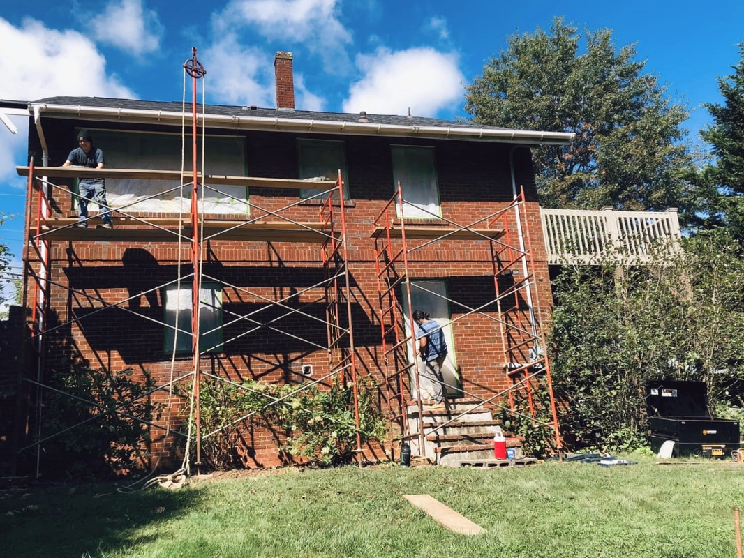Living Stone Masonry team on scaffolding, restoring a brick home
